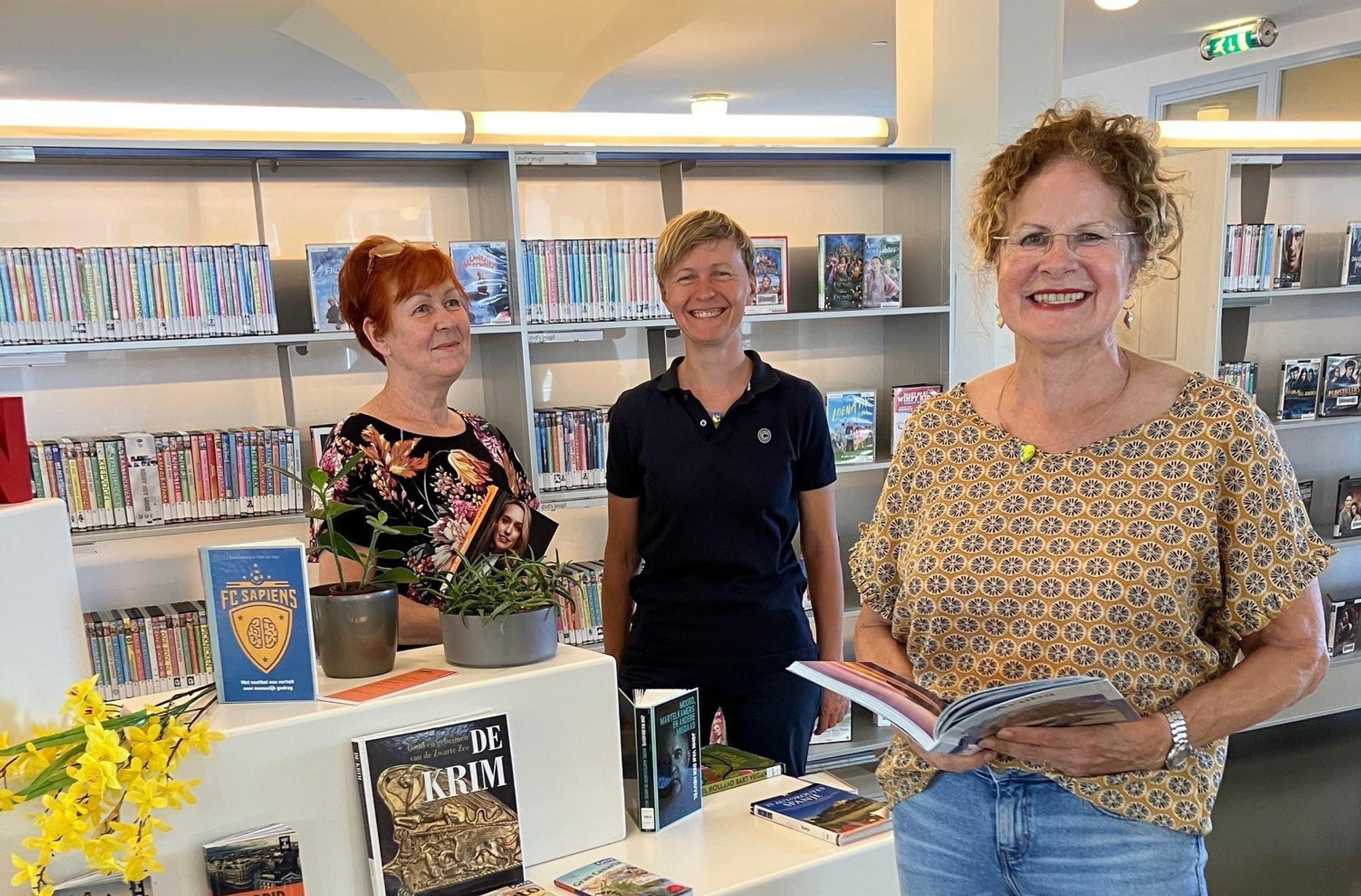 Drie vrouwelijke SCHUNCK-vrijwilligers in de bibliotheek.