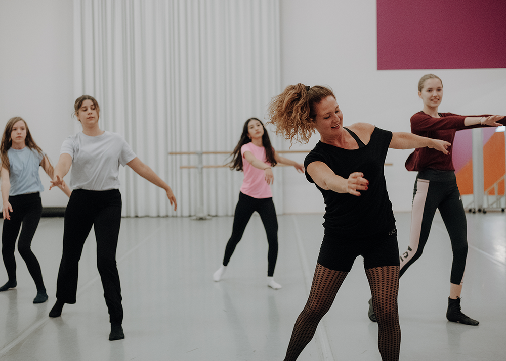 Portret Stephanie Rijpkema, tijdens dansles, samen met leerlingen aan het dansen. 
