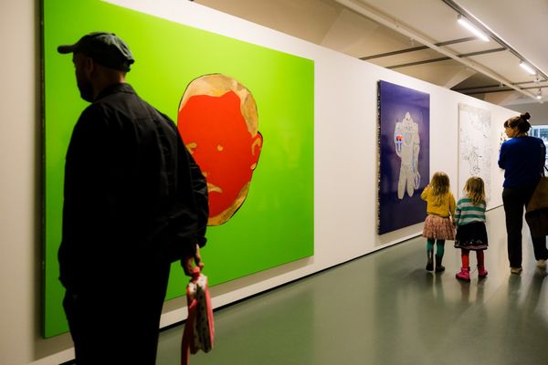 Bezoekers, waaronder twee kinderen, bekijken kleurrijke schilderijen in de tentoonstelling Rooted in Change in SCHUNCK Museum.