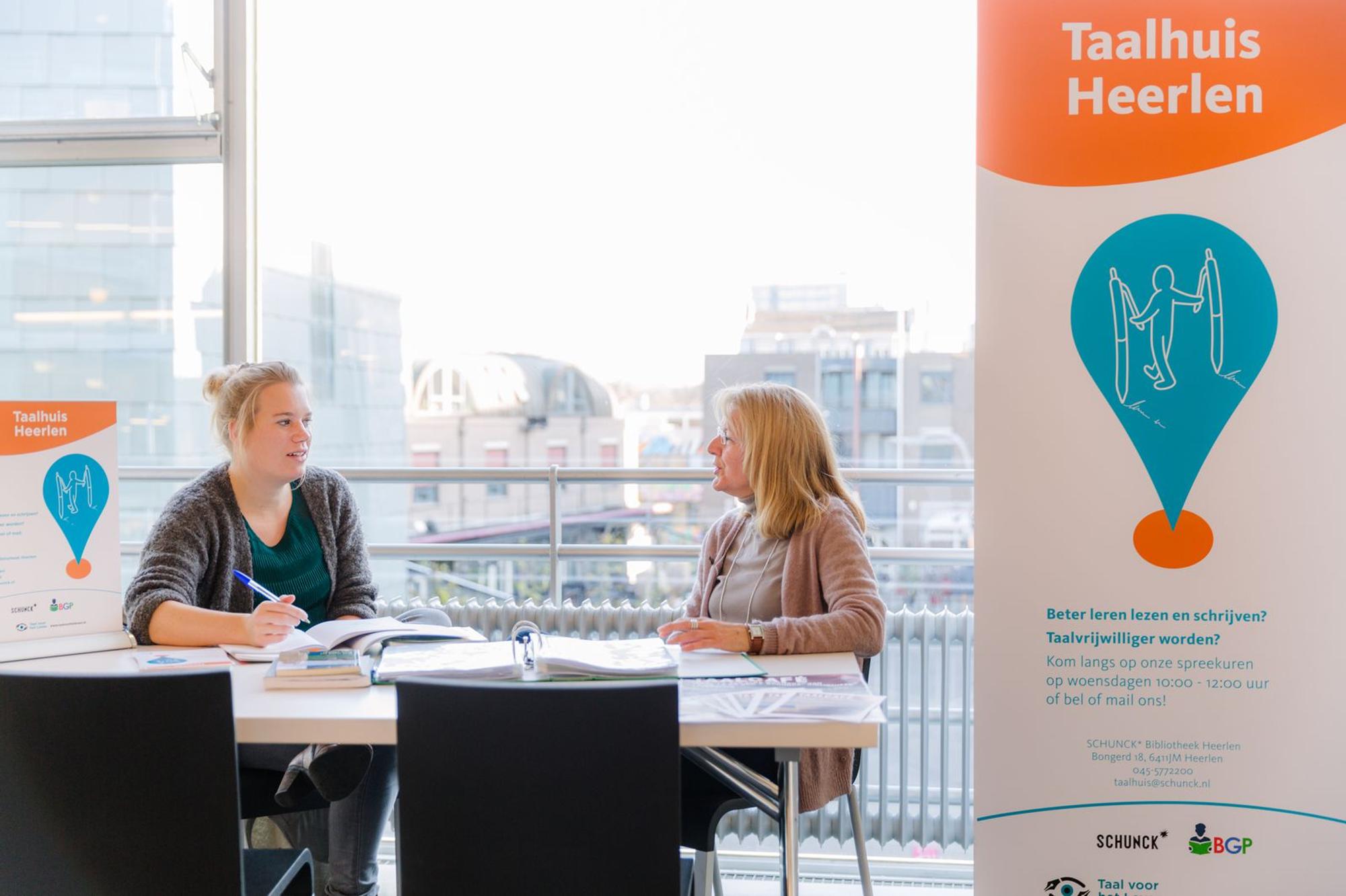 Taalvrijwilligers zitten aan tafel en geven begeleiding.