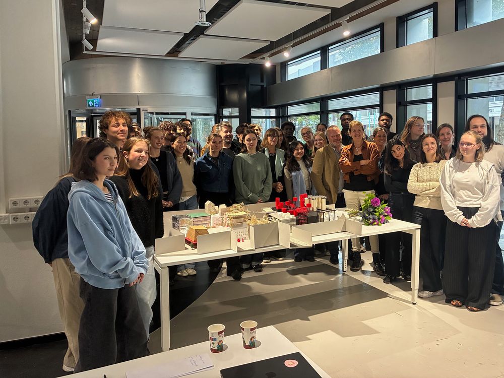 Groepsfoto van studenten en begeleiders van de 36e Euregionale Architectuurprijs tijdens de workshop Knowledge City Heerlen. De groep staat achter een grote architectuurmaquette met verschillende ontwerpen.