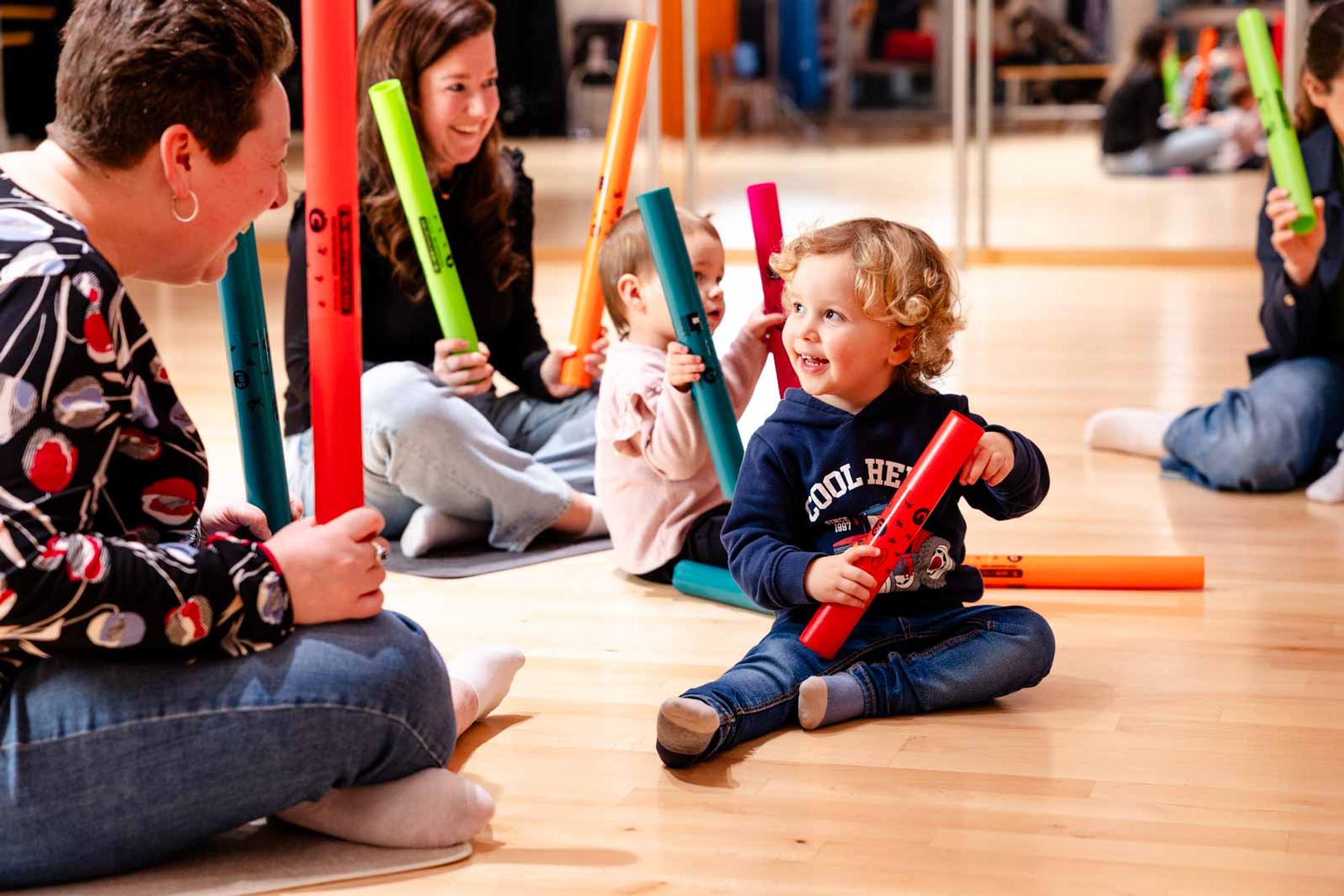 Jonge kinderen maken muziek met kleurrijke boomwhackers tijdens een les.