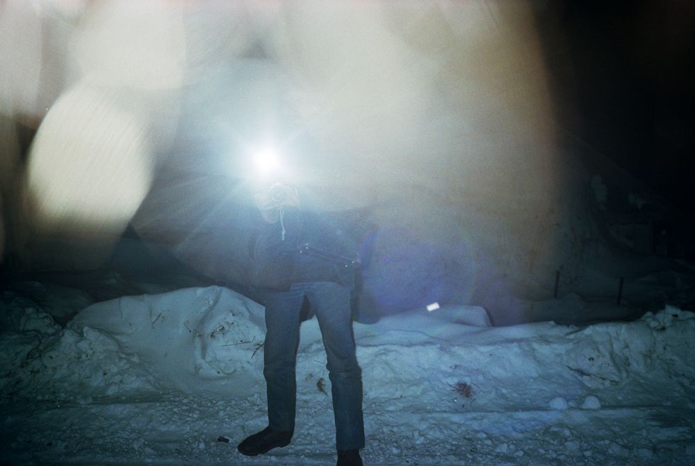Fotografie 'At the Mines' van Bertien van Manen (1994), Apanas, Siberië. Persoon in de sneeuw, onherkenbaar door de flits, alleen de benen zijn zichtbaar.
