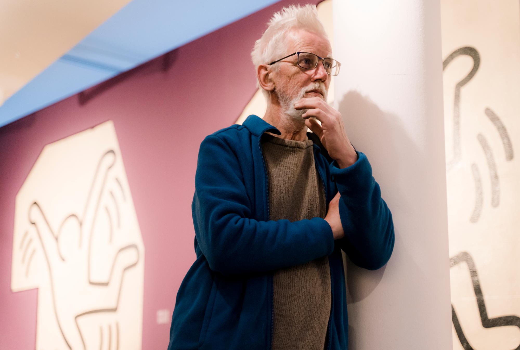 Vrijwilliger Ger Van Puffelen Bibliotheek leunt tegen pilaar in de museumzaal.