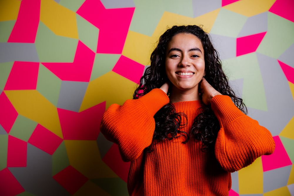 Portret van een jonge vrouw voor een kleurrijke muurschildering.