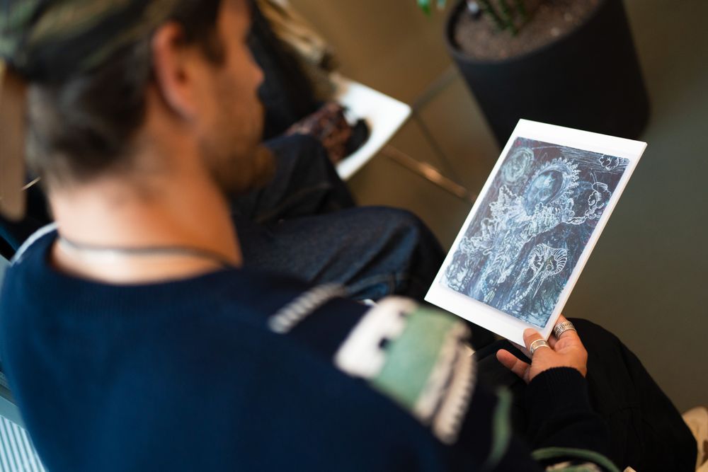 Een deelnemer van Life Cipher bekijkt geconcentreerd een kunstwerkafbeelding tijdens de selectie in het Kunstdepot van SCHUNCK. Foto: Miko Brepols.