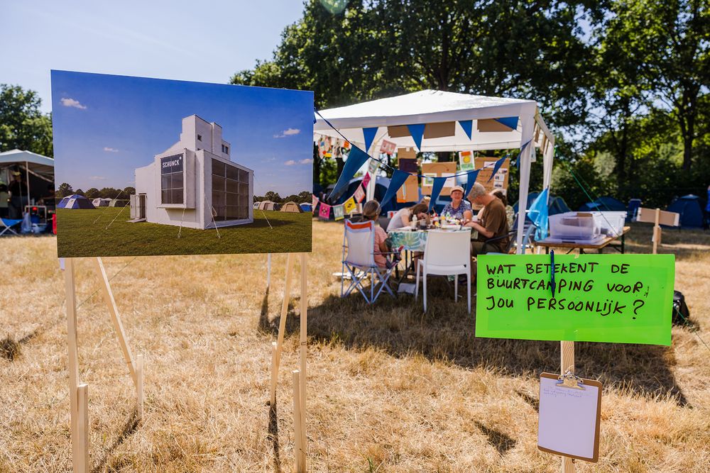 Een afbeelding van een Glaspaleis-tent en een bord met de vraag ‘Wat betekent de Buurtcamping voor jou persoonlijk?’ staan op het campingterrein.