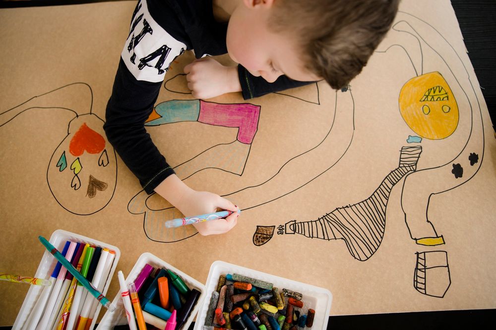 Bovenaanzicht van een jongetje die met stift aan het tekenen is. 