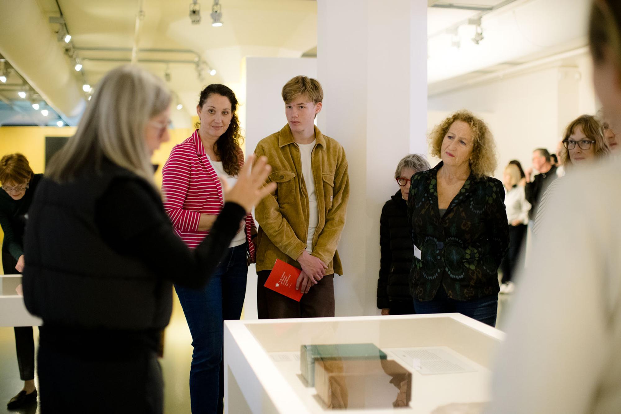 Rondleider en bezoekers staan bij vitrine tijden expositie Andy Warhol Vanitas. 