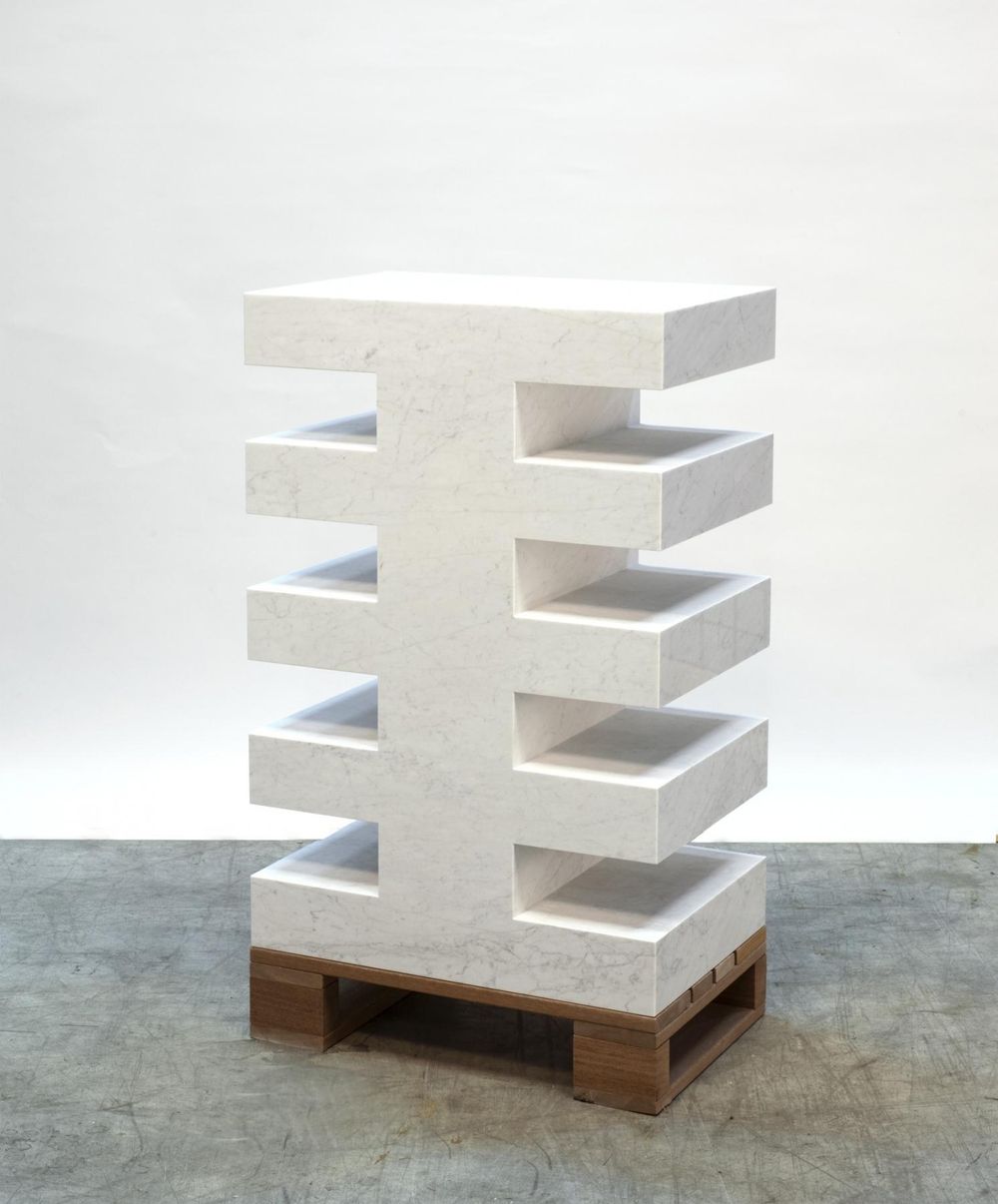 Wit marmeren sculptuur met een geometrisch patroon van horizontale en verticale lijnen, geplaatst op een houten sokkel. Aan beide zijden steken vijf symmetrisch geplaatste planken uit.