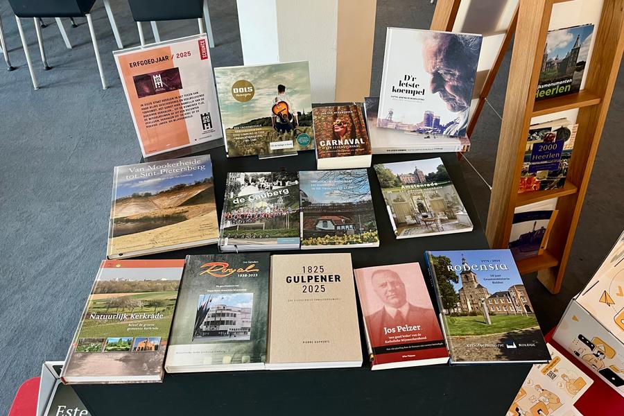 Tafel in een bibliotheek met een selectie boeken over Limburgs erfgoed, waaronder titels over carnaval, lokale geschiedenis, architectuur en streekcultuur, gepresenteerd onder de noemer Erfgoedjaar 2025.