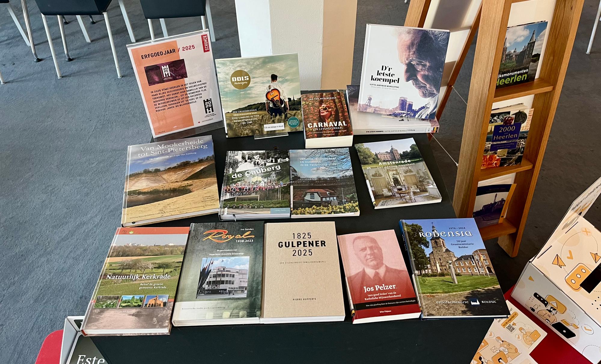 Tafel in een bibliotheek met een selectie boeken over Limburgs erfgoed, waaronder titels over carnaval, lokale geschiedenis, architectuur en streekcultuur, gepresenteerd onder de noemer Erfgoedjaar 2025.