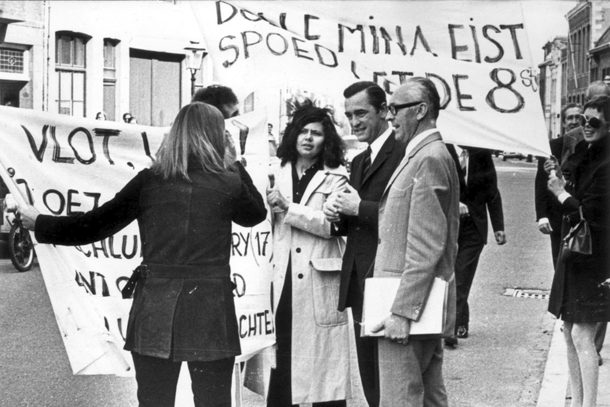 Zwart-wit foto van mensen die met vlaggen demonstreren voor feminisme.