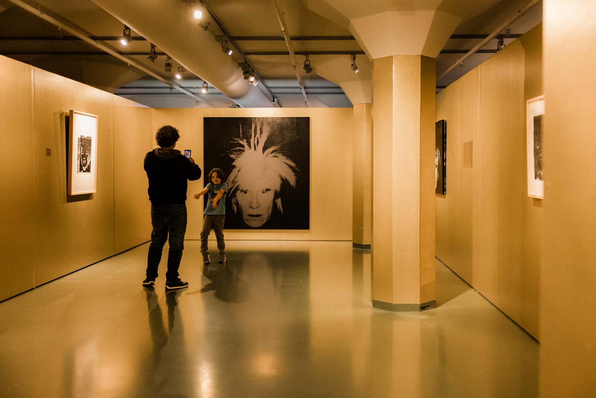 Man maakt een foto van kind voor zelfportret van Andy Warhol, in de gouden ruimte in het museum. 