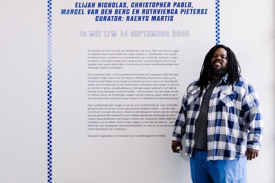 Curator Raenys Martis poseert bij de titelmuur van de tentoonstelling 'De Politiek van het Dagelijks Leven'.