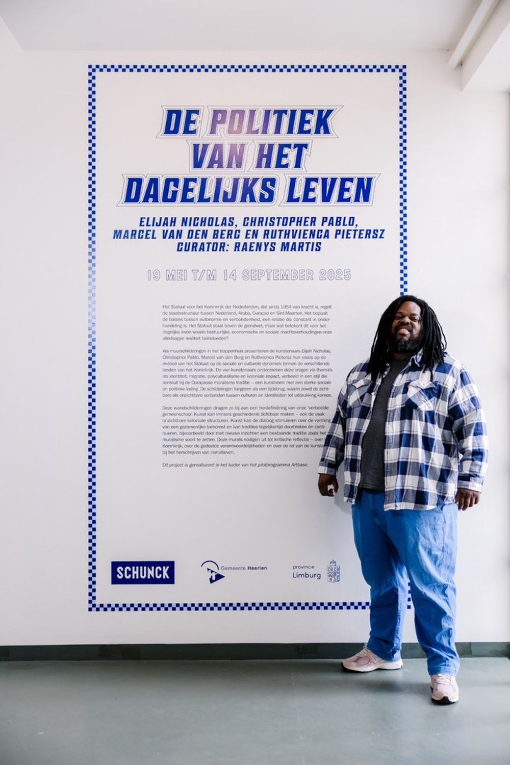 Curator Raenys Martis poseert bij de titelmuur van de tentoonstelling 'De Politiek van het Dagelijks Leven'.